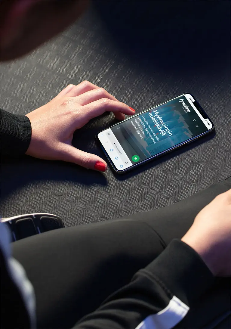 Henkilö istuu sohvalla ja käyttää matkapuhelinta.