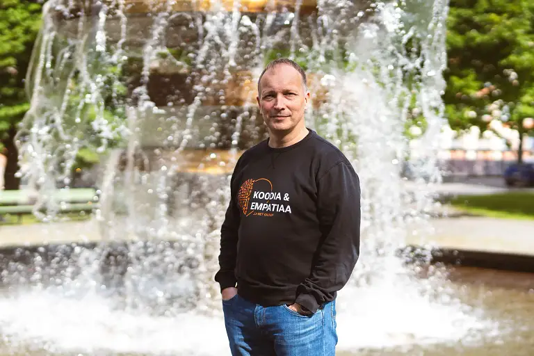 Mies seisoo suihkulähteen edessä puistossa.