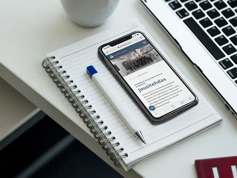 Puhelin kannettavan tietokoneen päällä kannettavan tietokoneen vieressä.