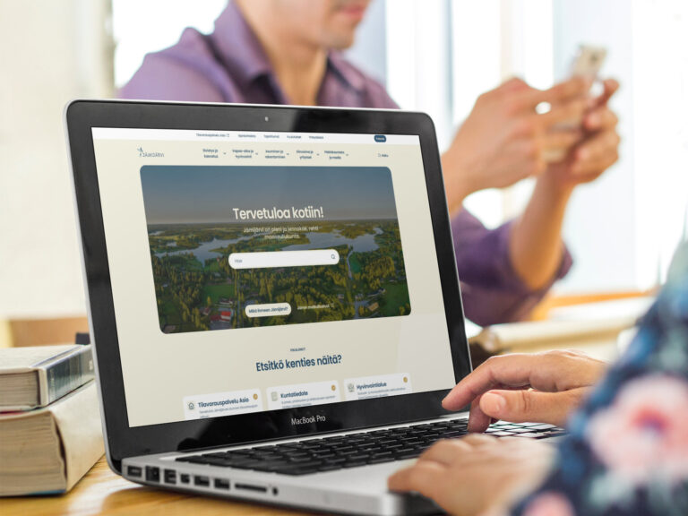 Mies ja nainen istuvat pöydän ääressä ja katsovat kannettavaa tietokonetta.